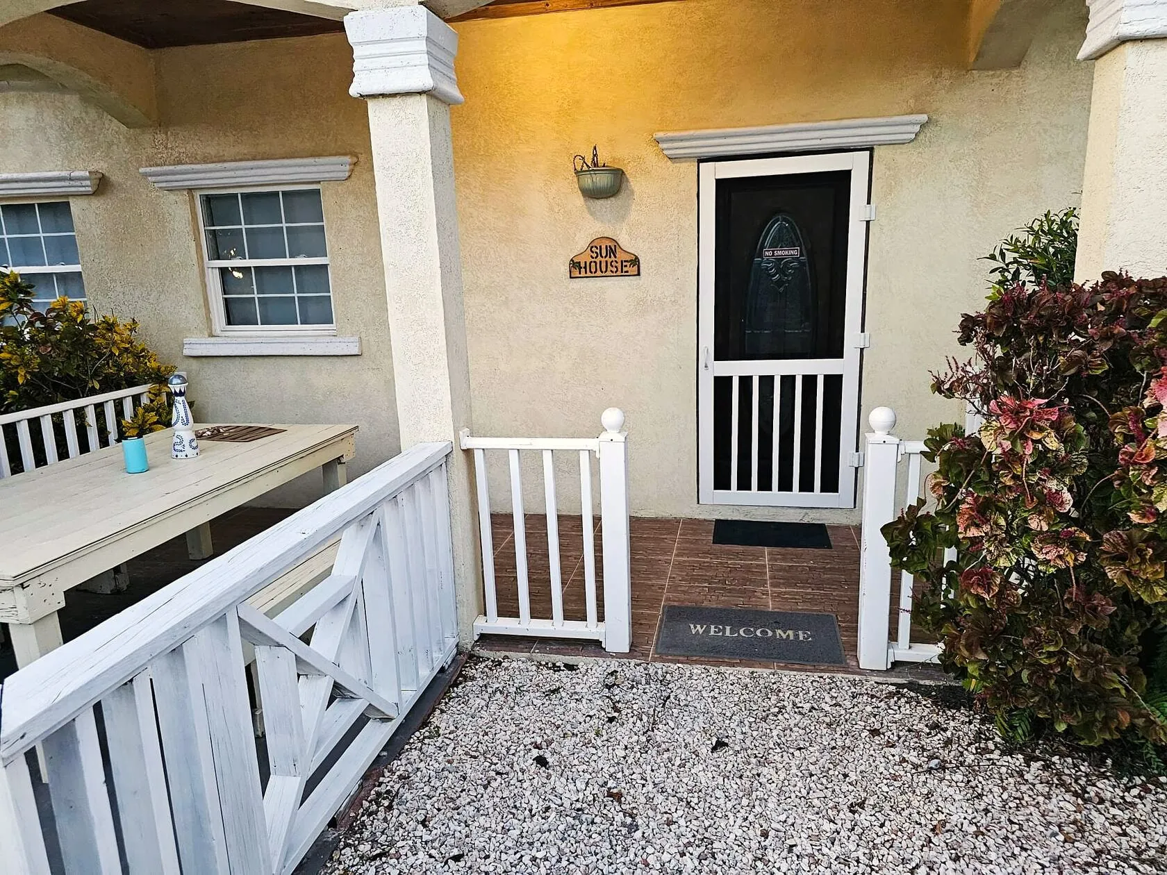 Sun Villa front entrance with porch dining table and welcome mat